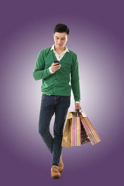 Holding shopping bags and using cellphone — Stock Photo, Image