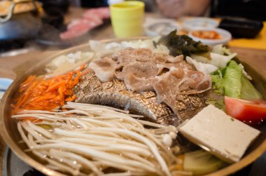 Bir restoranda bakır ızgara tepsisi üzerinde Kore barbeküsü