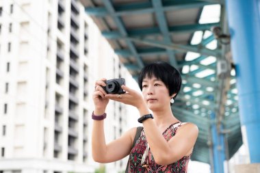 Dışarıdaki tren istasyonunda dijital kamera kullanan Asyalı bir kadın.