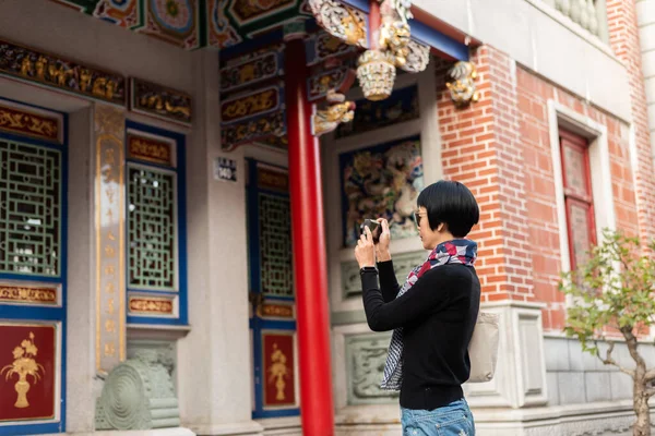 現代のアジアの女性は古い中国の建物を旅するカメラを持っています — ストック写真