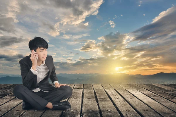 Asiatiska affärsman ta ett samtal och sitta på marken — Stockfoto