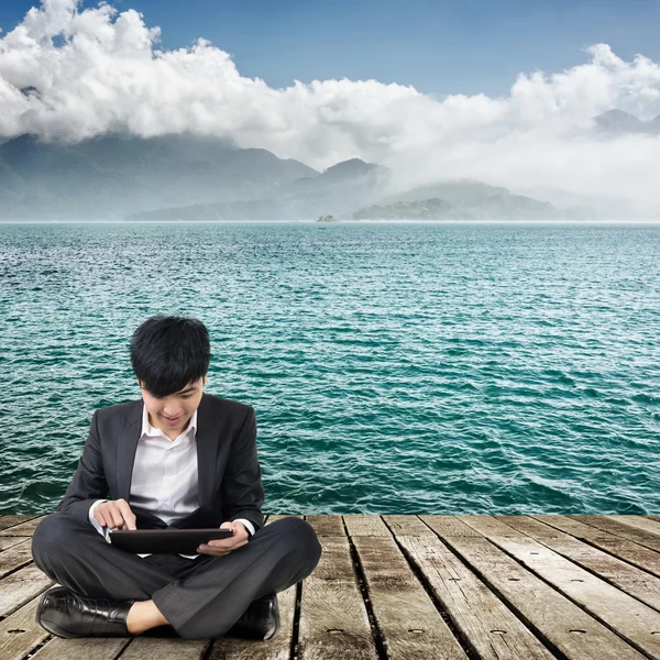 Asian business man using pad and sit on ground — Stock Photo, Image