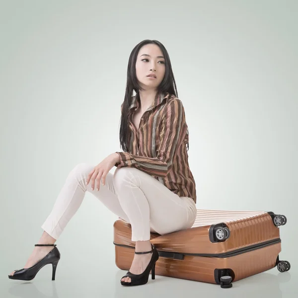 Азиатская женщина думает и сидит на багаже — стоковое фото