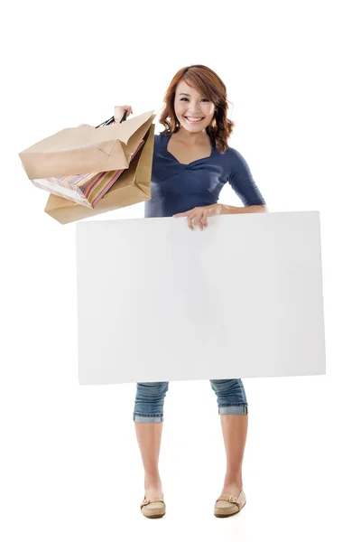 Shopping woman holding bags and blank board — Stock Photo, Image