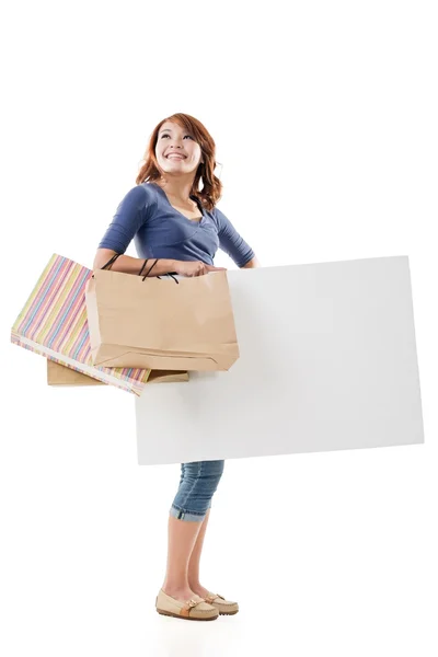 Shopping woman holding bags and blank board — Stock Photo, Image