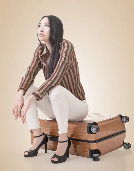 Asiatische Frau denken und sitzen auf einem Gepäck — Stockfoto