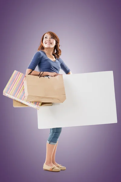 Shopping woman holding bags and blank board — Stock Photo, Image