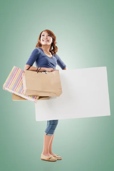 Mujer de compras sosteniendo bolsas y tablero en blanco — Foto de Stock