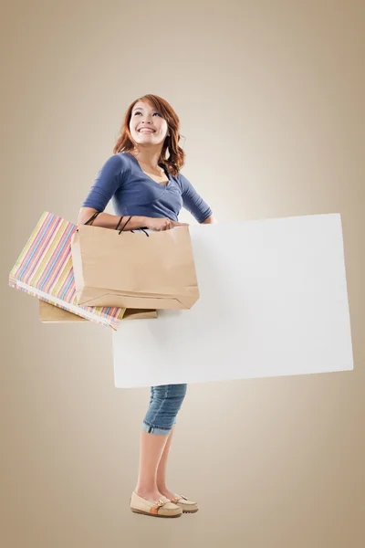 Shopping woman holding bags and blank board — Stock Photo, Image