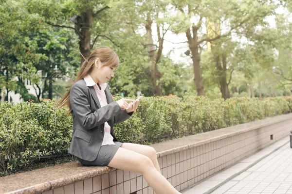 Азиатская деловая женщина пользуется мобильным телефоном — стоковое фото