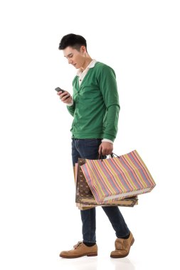 alışveriş torbaları tutarak ve cep telefonu kullanarak