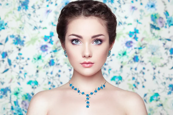 Portrait of young beautiful woman on a background of flowers — Stock Photo, Image