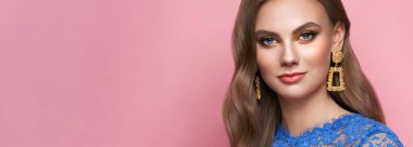 Mükemmel makyajlı esmer kız. Kıvırcık saçlı güzel bir model kadın. Bakım ve güzellik ürünleri. Modaya uygun altın makyajlı bayan. Pembe arka planda mücevherleri olan bir model