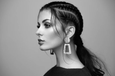 Mükemmel makyajlı esmer kız. Kıvırcık saçlı güzel bir model kadın. Bakım ve güzellik ürünleri. Saçları örgülü bir kadın. Mücevherleri olan bir model. Siyah beyaz fotoğraf