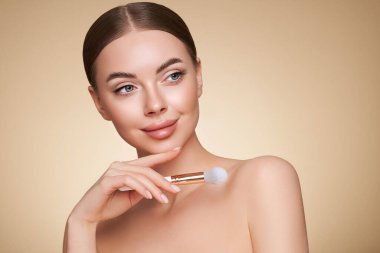 Temiz tenli güzel bir genç kadın portresi. Makyaj fırçası olan bir model. Kozmetik, güzellik ve kaplıca