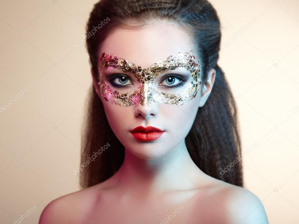 Beautiful young woman in gold mysterious mask