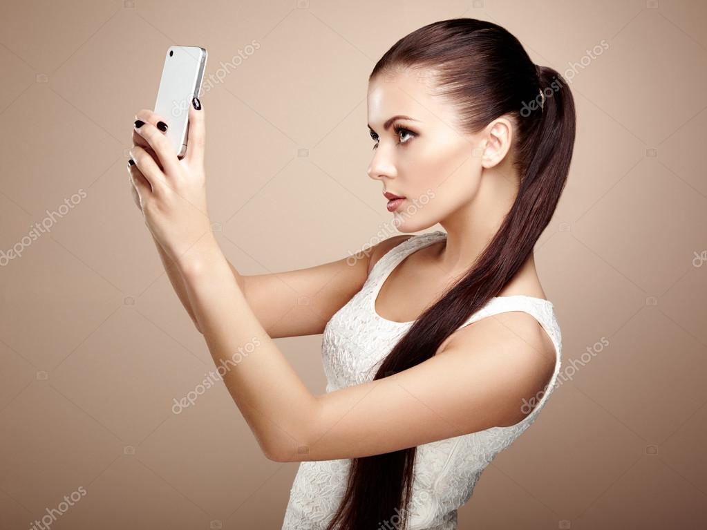 живые гаджеты с улыбкой. утопать в цветах. девушка визажист фоткает себя закрывая телефоном. красивые руки девушки с маникюром. салон красоты девушка.