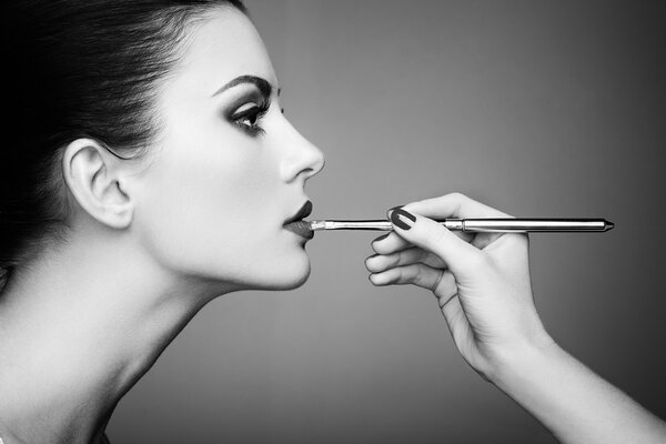 Makeup artist applies lipstick