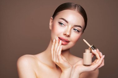 Temiz tenli güzel bir genç kadın portresi. Makyaj şişesi olan bir model. Kozmetik, güzellik ve kaplıca