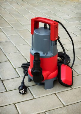 Household submersible pump with plastic housing  on stone floor of courtyard clipart