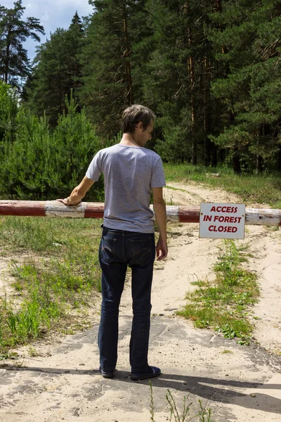 火災の危険期間に森の中で署名を禁止する前に男が立っている — ストック写真