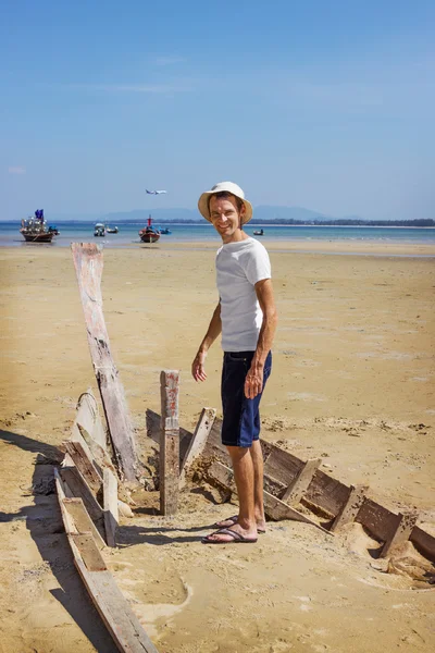 Счастливый турист, стоящий на разбитой лодке. — стоковое фото
