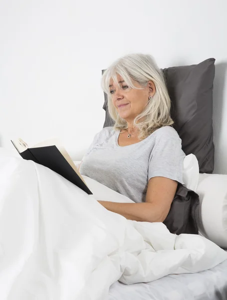 Vrouw lezen van een boek in bed — Stockfoto