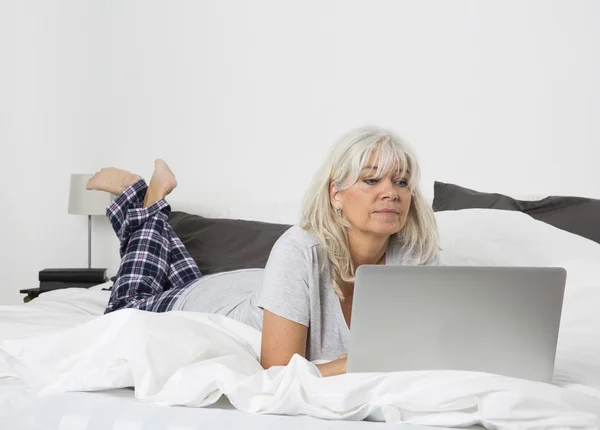 Mid Age woman with a laptop in bed — Stock Photo, Image