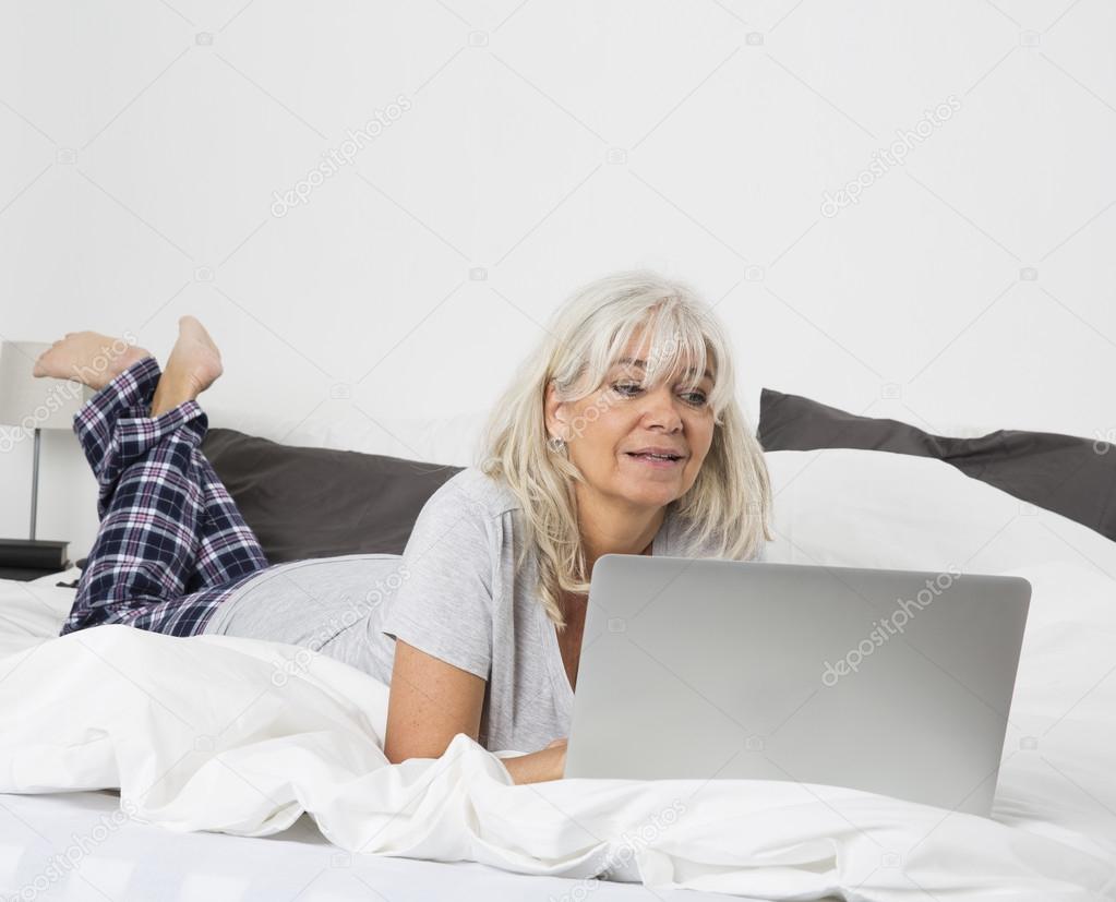 Mid Age woman with a laptop in bed