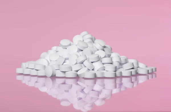 Stos tabletki do różowy tło — Zdjęcie stockowe
