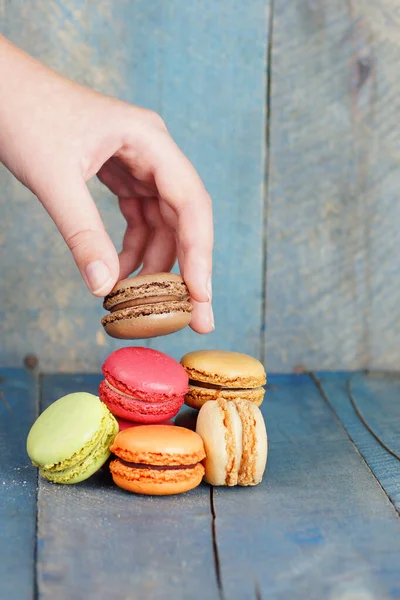 Vertical Macarrón Recogida Mano Fondo Azul Madera Vieja — Foto de Stock