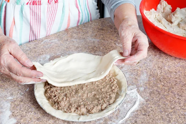 Бабусині руки роблять м'ясний пиріг — стокове фото