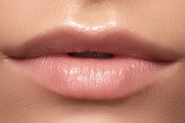 Kadının dudakları ile moda doğal bej ruj makyaj close-up. Yatay makro seksi soluk lipgloss makyaj