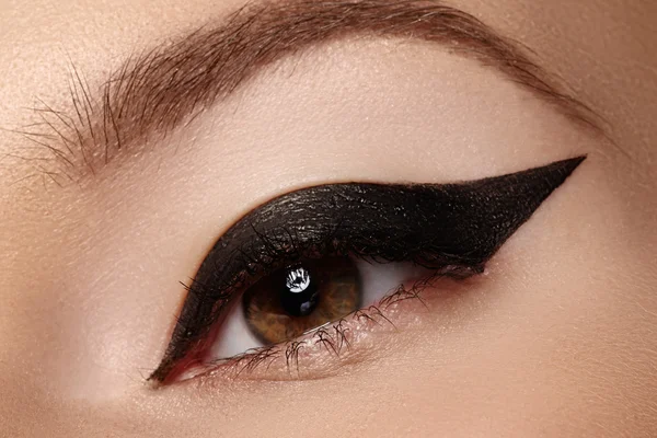 Beautiful female eye with sexy black liner makeup. Fashion big arrow shape on woman's eyelid. Chic evening make-up Stock Photo