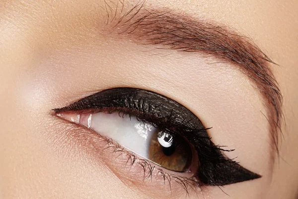 Vackra kvinnliga ögat med sexig svart bärmaterial makeup. Fashion stora Pilform på kvinnans ögonlocket. Chic kvällen make-up Stockbild