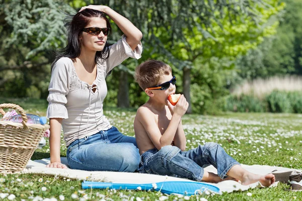 Woman sitting on grass with son — Zdjęcie stockowe
