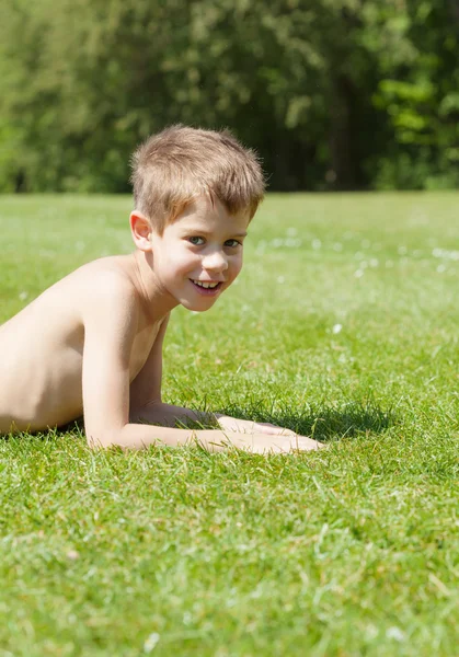 Kluk leží na trávě — Stock fotografie