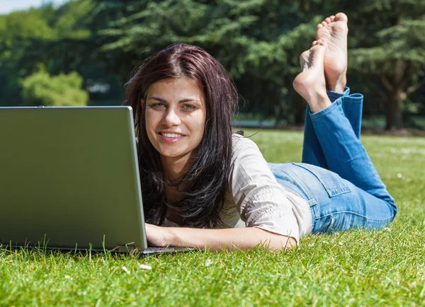 Woman with laptop on grass — Stok fotoğraf