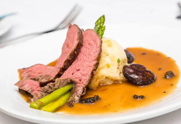 Carne de bovino fatiada com cogumelos e batatas de espargos — Fotografia de Stock