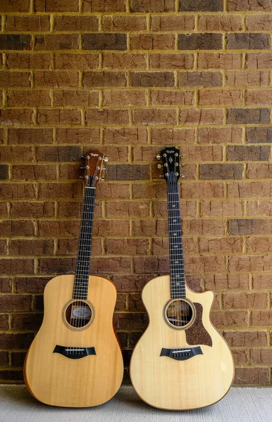 Two Taylor Guitars on Brick Wall — Stock Photo, Image