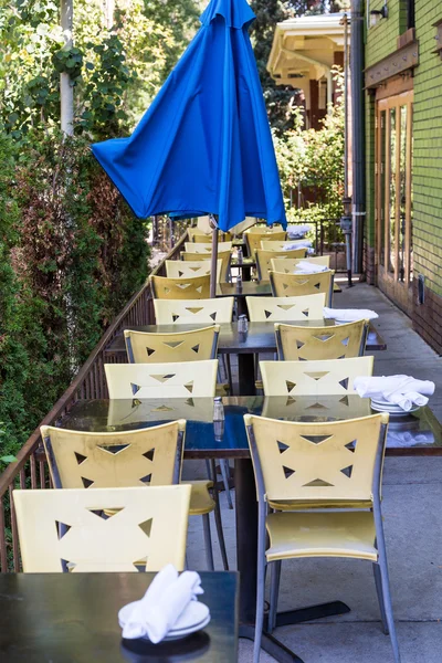 Chaises en plastique et parapluie bleu au patio du restaurant — Photo