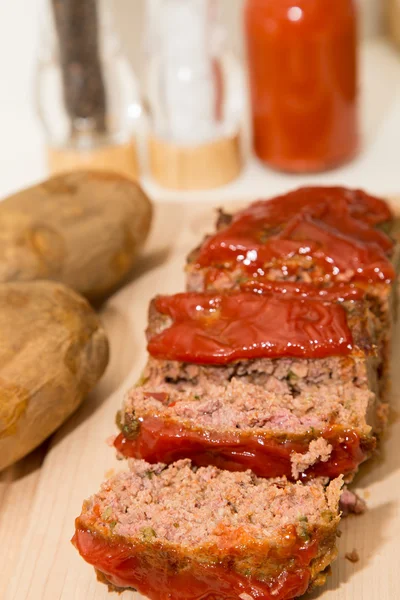 Ahşap tahta üzerinde dilimlenmiş rulo köfte ve fırında patates — Stok fotoğraf