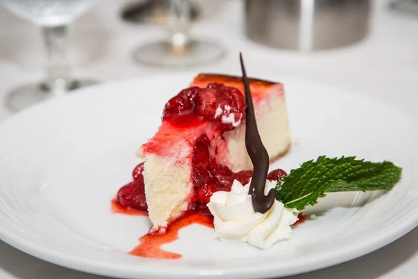 Strawberry cheesecake gegarneerd met slagroom en muntblad — Stockfoto