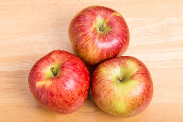 Três maçãs vermelhas na mesa de madeira — Fotografia de Stock