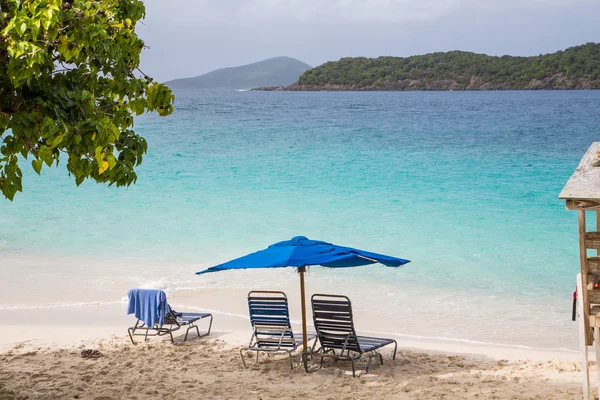 Kanapami pod niebieski parasol na tropikalnej plaży — Zdjęcie stockowe
