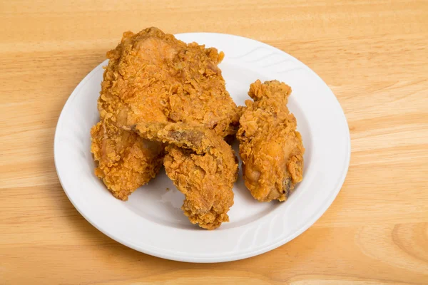 Жареный цыпленок на малой белой тарелке и деревянном столе — стоковое фото