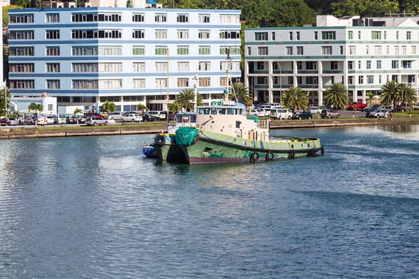 Oude groene sleepboot door moderne gebouwen — Stockfoto