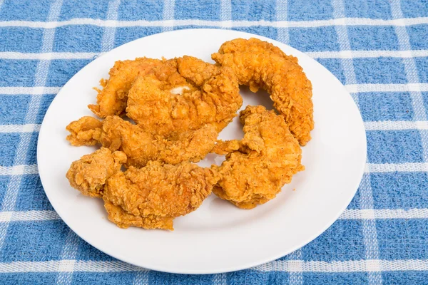 Hühnerstreifen auf weißem Teller und blauem Tischset — Stockfoto