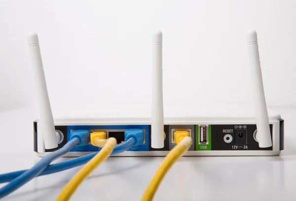 Router wireless bianco con cavi blu e gialli — Foto Stock