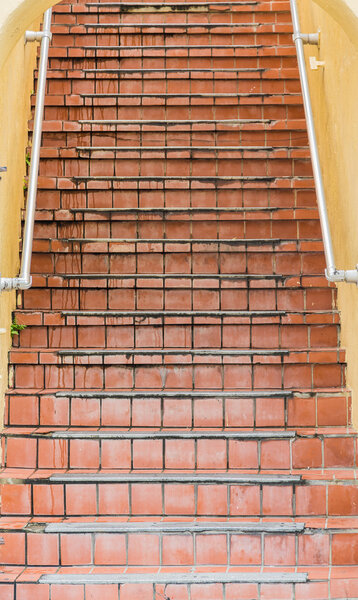 Old yellow plaster building with red quarry tile steps